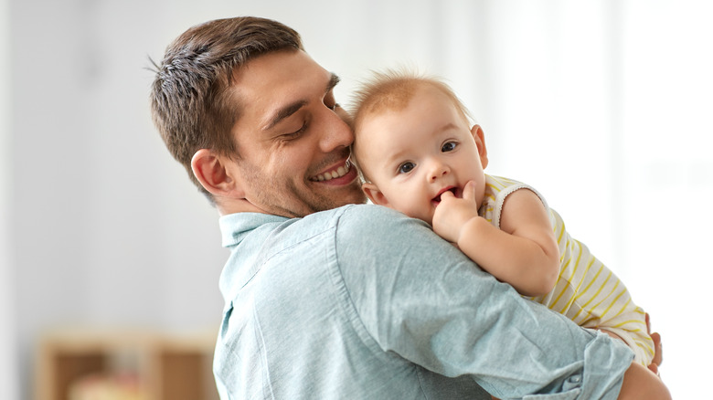 father cuddling his teething child