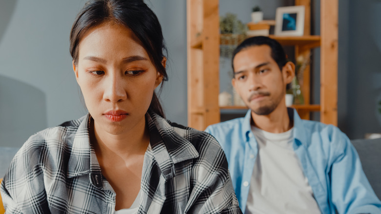 Couple sitting on couch looking upset