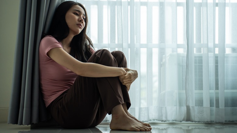 Upset woman sitting by the window