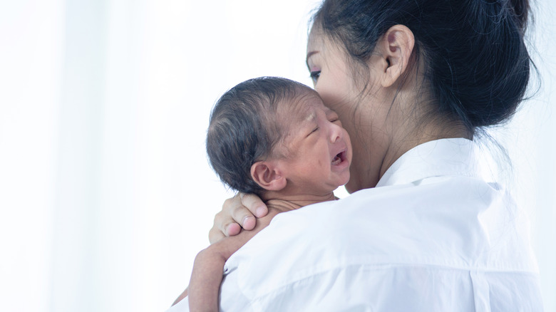 mother holding crying newborn baby