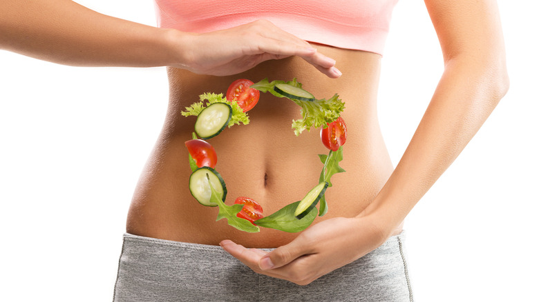 woman holding stomach with vegetables