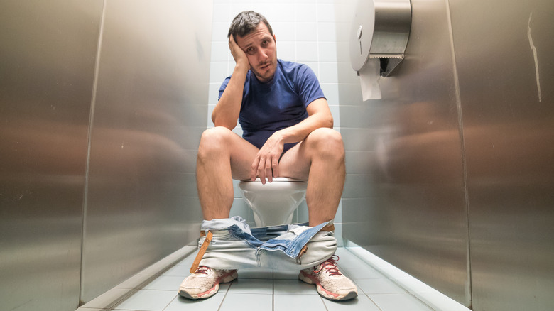 man on toilet looking dismayed