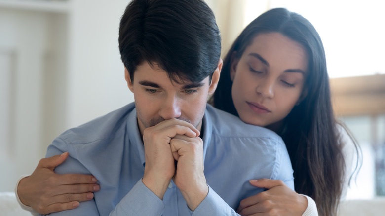 grieving man receiving support from woman