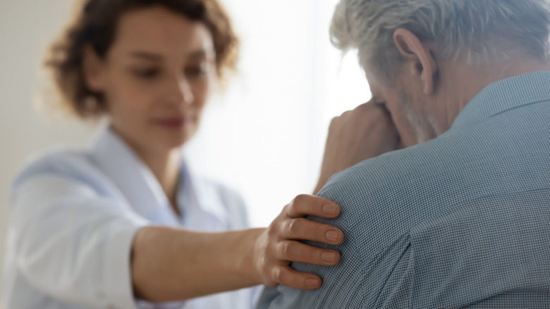 Doctor supporting grieving elderly patient