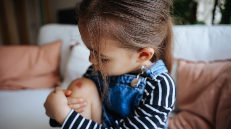 Young girl looking at scraped knee