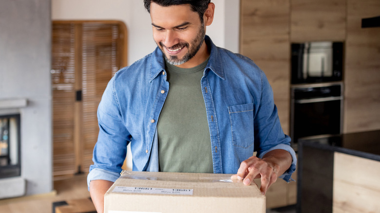 A smiling man holding a delivery package at home