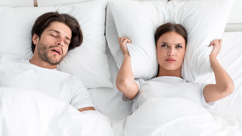 woman wide awake in bed while man snores