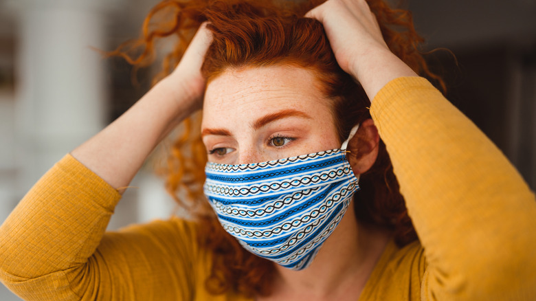 Woman wearing mask touching hair