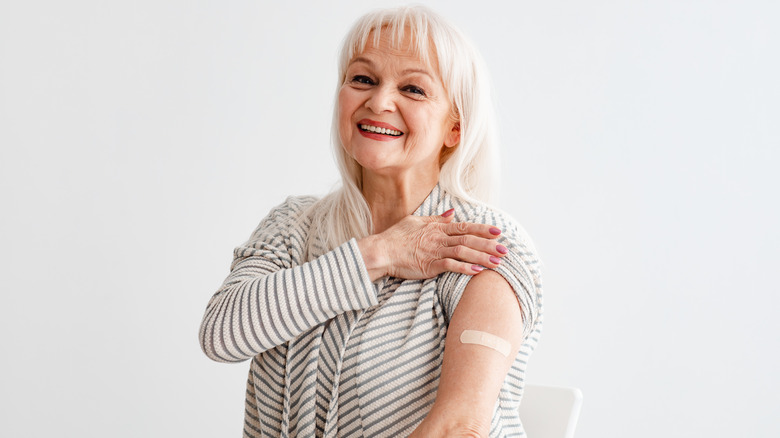 older woman showing band-aid on arm