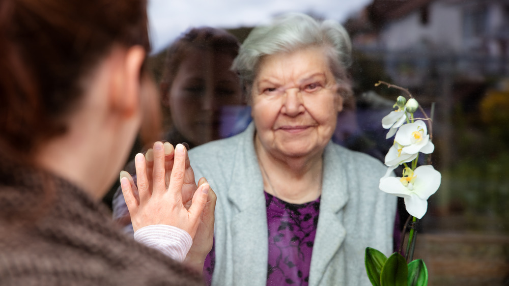 Grandmother and relative greeting each other through window