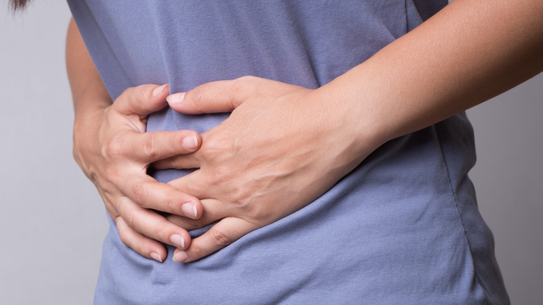 close up of a woman in a blue shirt holding her stomach