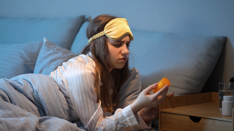 A woman in bed looking at her medicine bottle