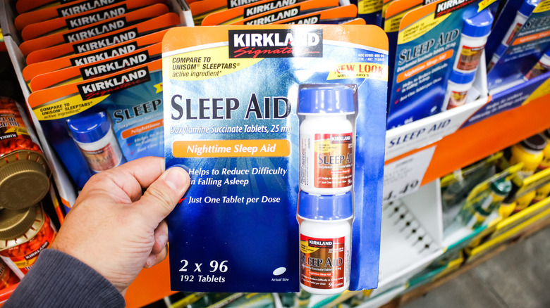 A hand holding a package of Kirkland Signature Sleep Aid