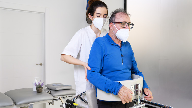 Doctor assisting ALS patient into supportive equipment