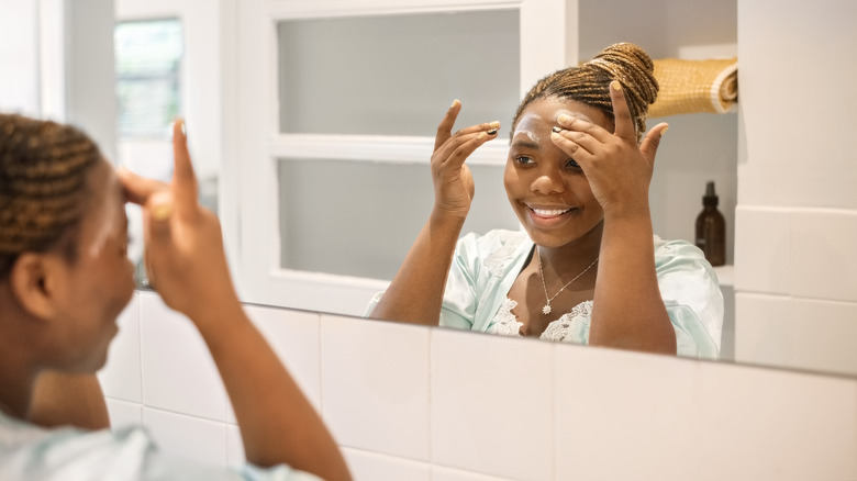 Woman applying cream to forehead