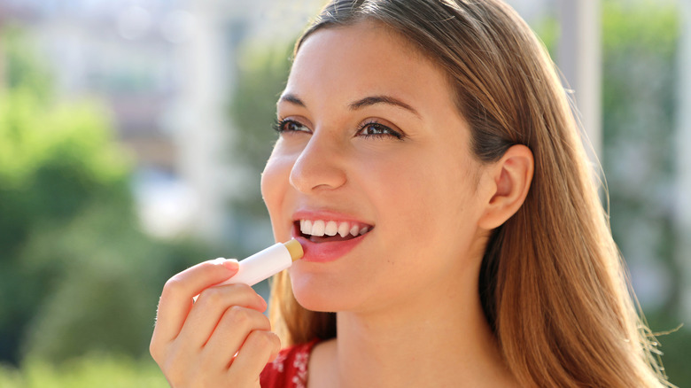 woman applying lip balm while outdoors