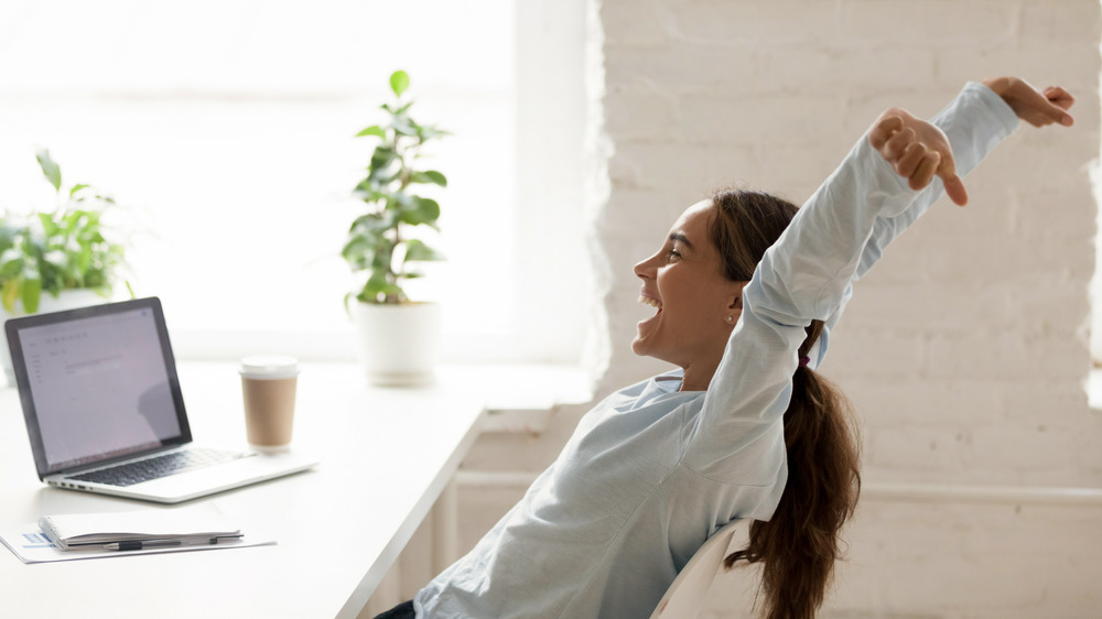 Woman stretches in front of her computer