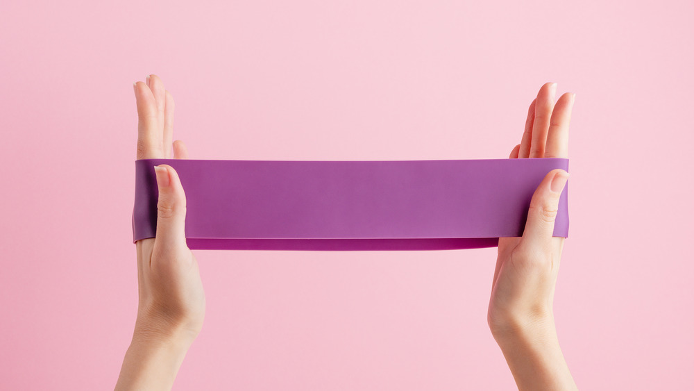 Woman holding a purple resistance band.