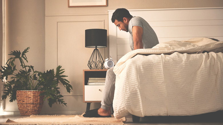 Concerned man sitting on edge of bed