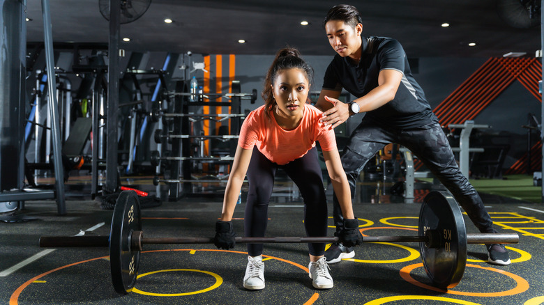 a trainer teaching a woman how to deadlift 