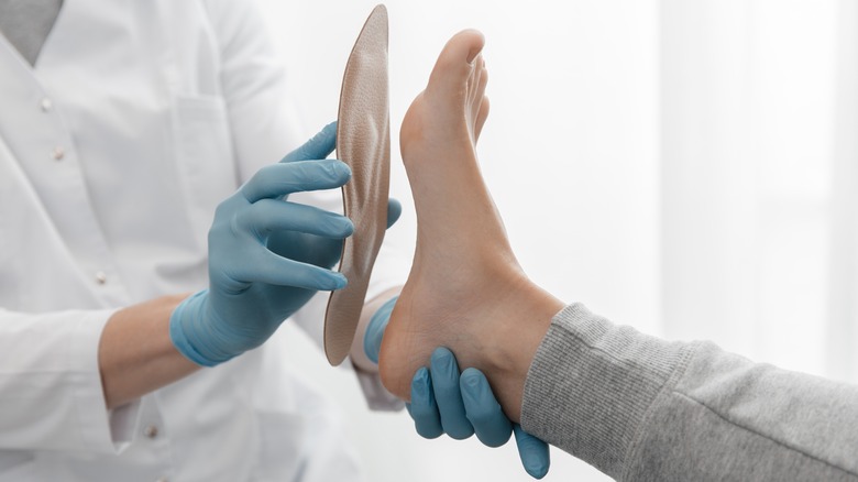 Doctor placing orthopedic insert up against patient's foot