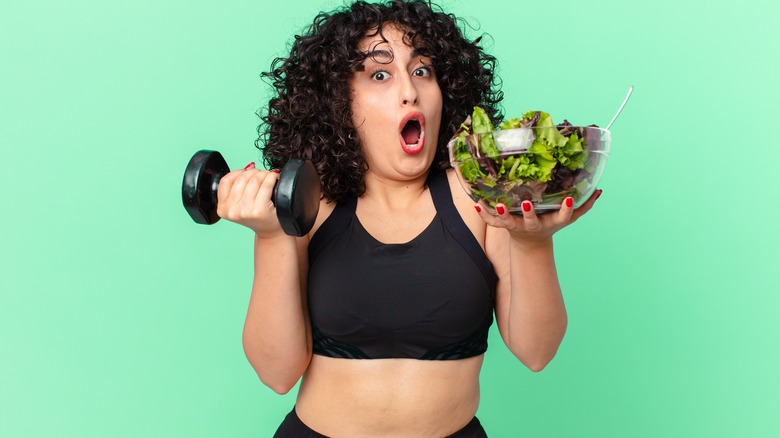 a person holding a salad and weights 