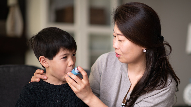 Caretaker helping child with inhaler
