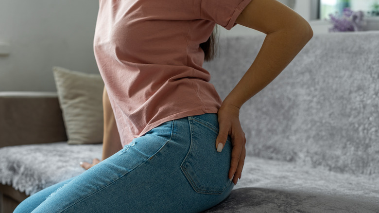 woman sitting on a couch with a hand on her butt