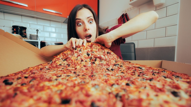 woman eating an extremely large pizza