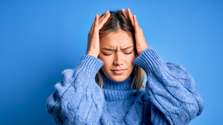 woman holding head in hands