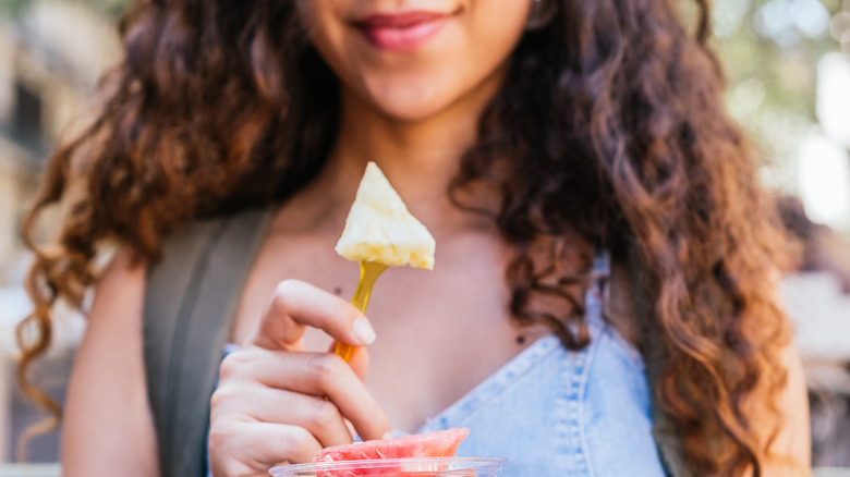 Woman holding pineapple slice on fork