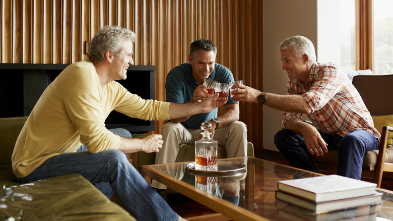 Three older men toasting their glasses of whiskey