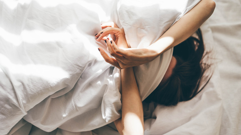 A sleepless woman covering her head with her duvet