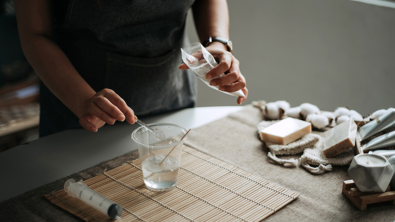 woman pouring baking soda into a glass of water