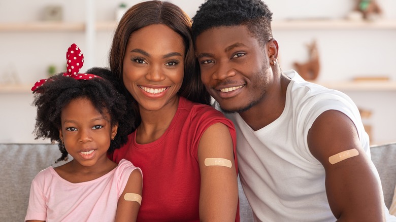 Family of 3 with bandages on their upper arm from vaccine shot