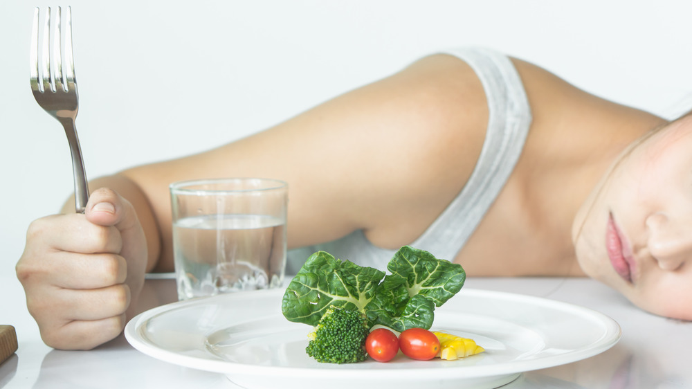 a woman with her head on the table to tired to eat 