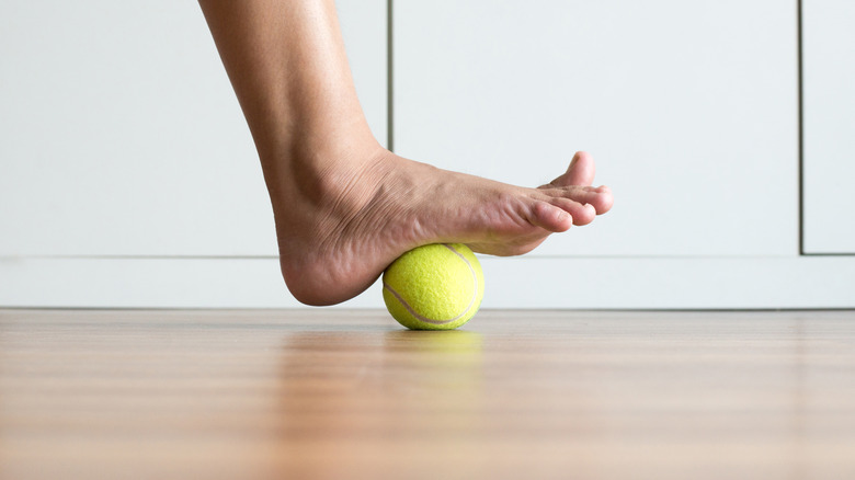 massaging foot with tennis ball