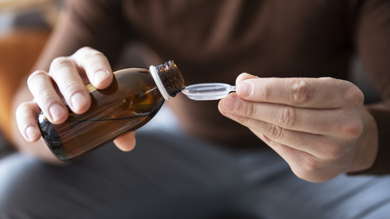 Hands pouring spoon of cough syrup