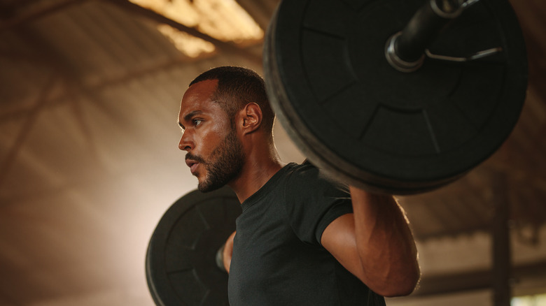 man doing squats with barbell 