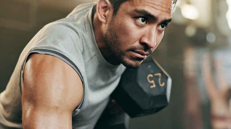 serious man lifting 25 pound dumbbell