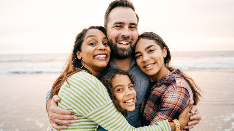 mixed family hugging each other at the beach