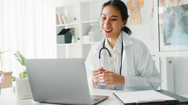 Physician smiling at laptop: telehealth concept