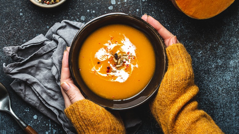 woman's hands holding bowl of soup