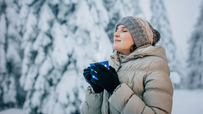 woman enjoying hot drink standing in snow