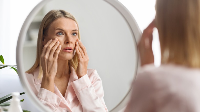 woman looking at her aging skin in mirror