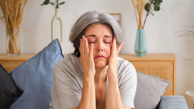 plus de 50 ans, femme assise sur un canapé, les mains sur le visage