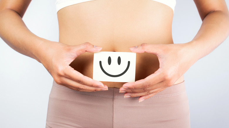 woman holding a smiley face in front of her belly