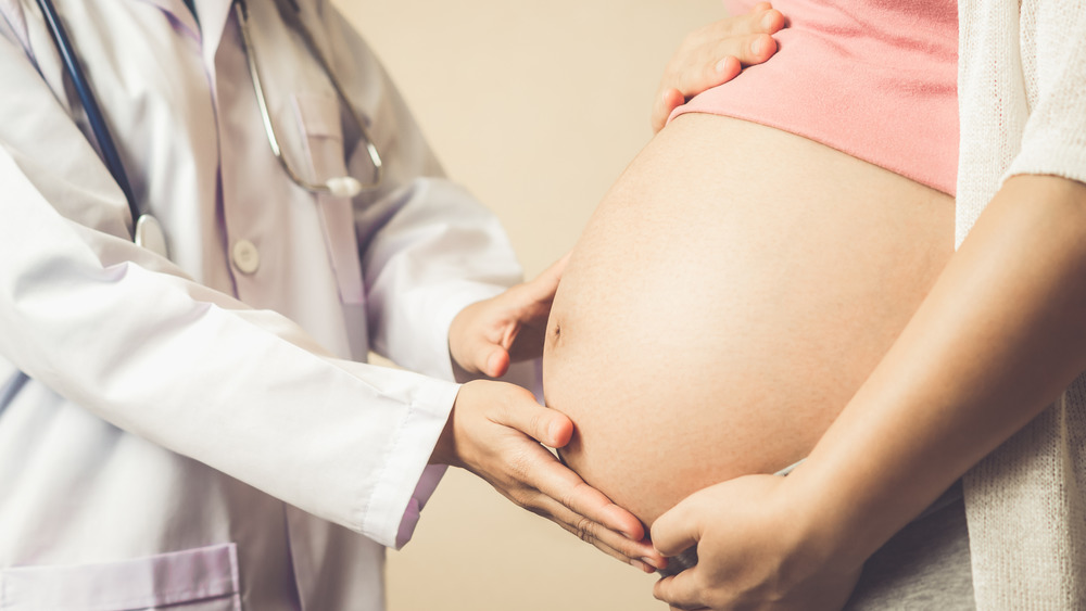 Pregnant woman holding stomach during doctor's visit