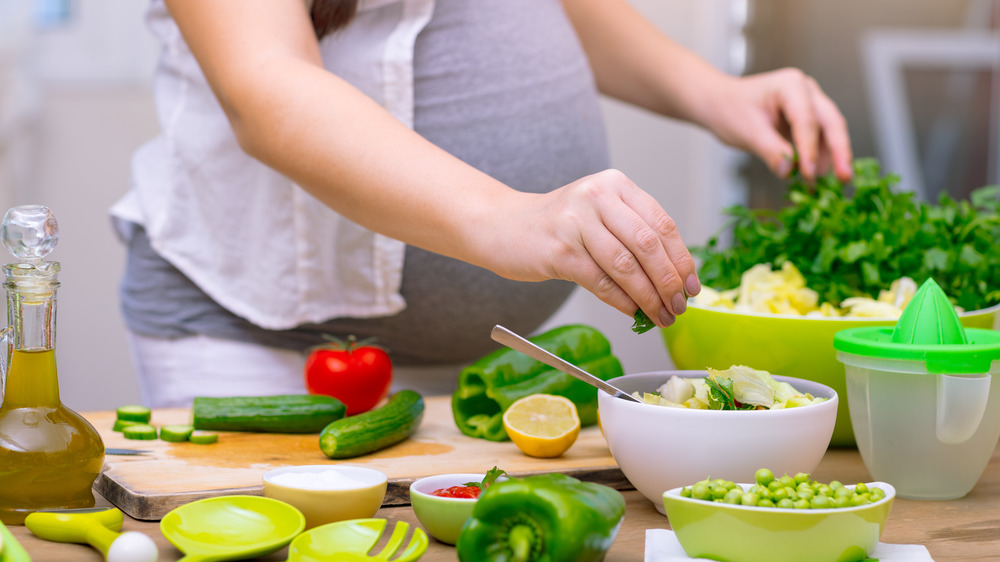 Pregnant woman cooking at home with vegetables