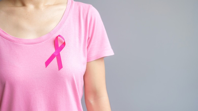A woman wears a pink breast cancer ribbon